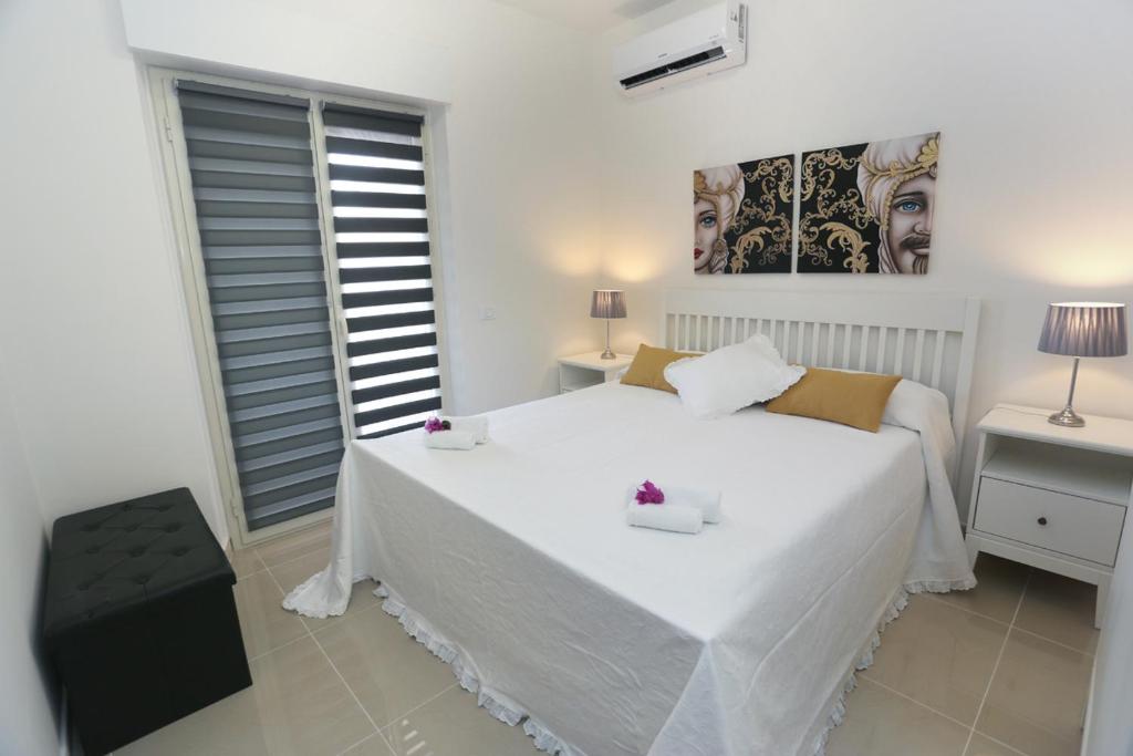 a white bedroom with a large white bed and a window at Naxos Sicilian Luxury Apartment in Giardini Naxos