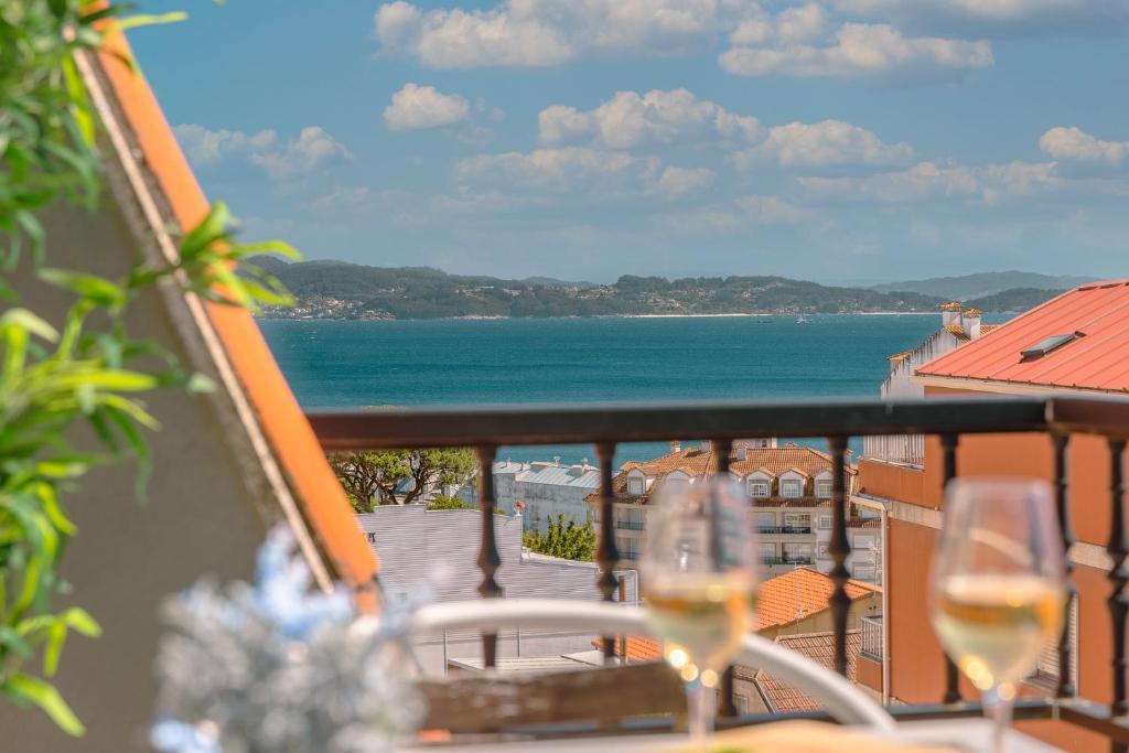 2 copas de vino sentadas en un balcón con vistas al océano en Apartamentos Ambitus Active, en Sanxenxo