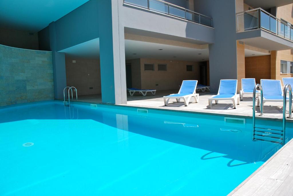 ein großer Pool mit Stühlen und ein Gebäude in der Unterkunft Whale - Apartment with Wi-Fi and heated pool in São Martinho do Porto