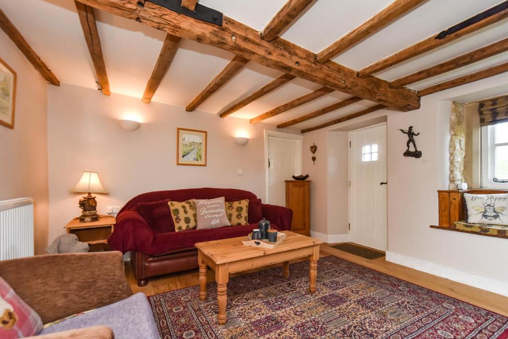 a living room with a red couch and a table at Old Horns Cottage, Higham Derbyshire in Alfreton