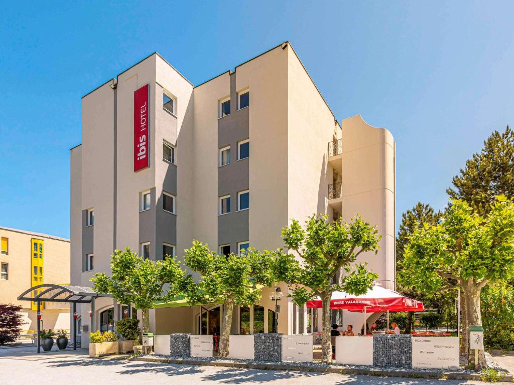 un hotel con alberi di fronte a un edificio di Ibis Sion a Sion