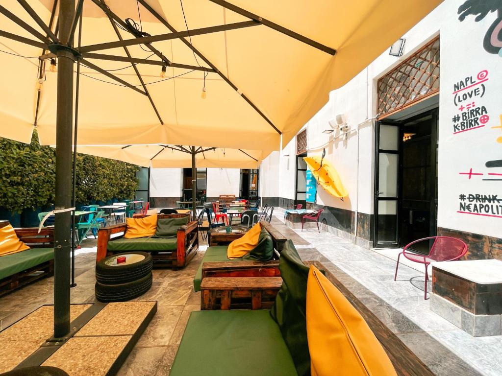 um pátio com sofás e cadeiras debaixo de um guarda-sol em NeapolitanTrips Hotel em Nápoles