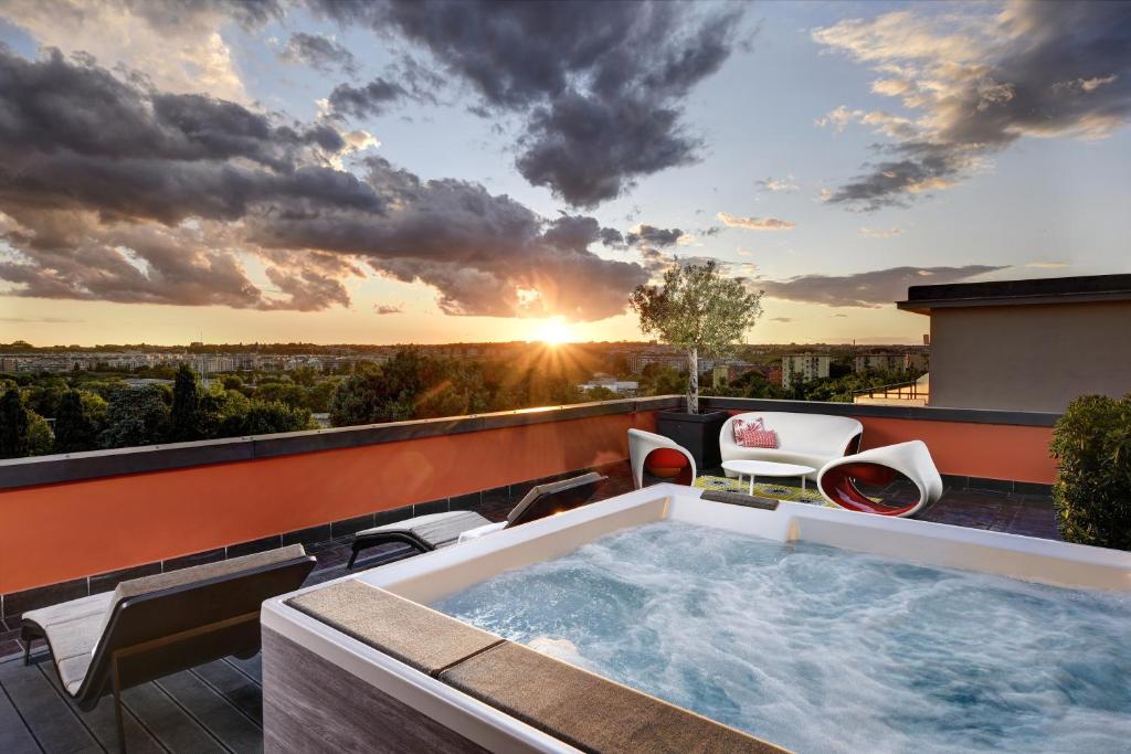 a hot tub on the roof of a house with the sunset at Hotel Pulitzer in Rome