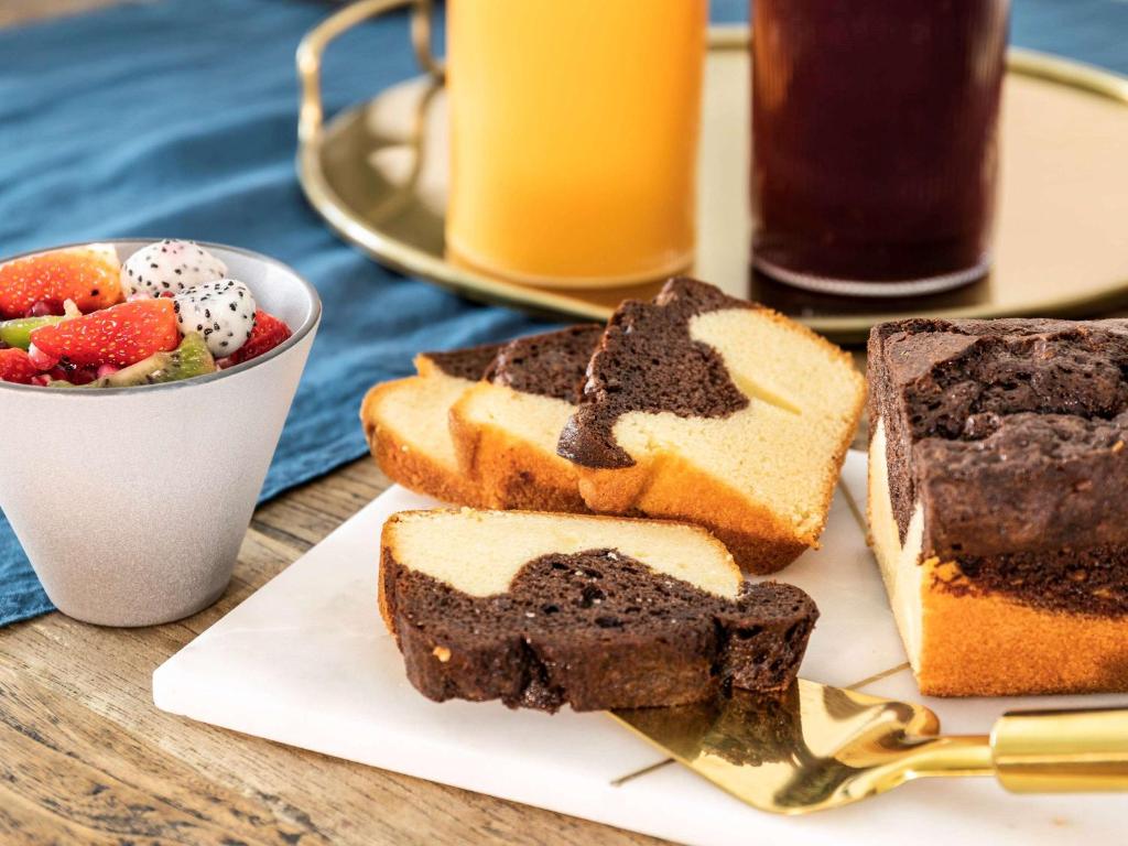 a plate of bread and a bowl of fruit and juice at Mercure Jakarta Batavia in Jakarta