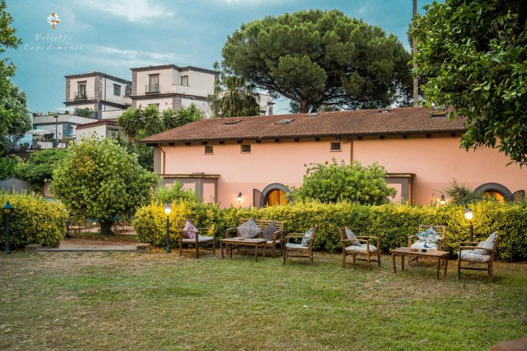 une cour avec des tables et des chaises devant une maison dans l'établissement Villetta Capodimonte, à Naples