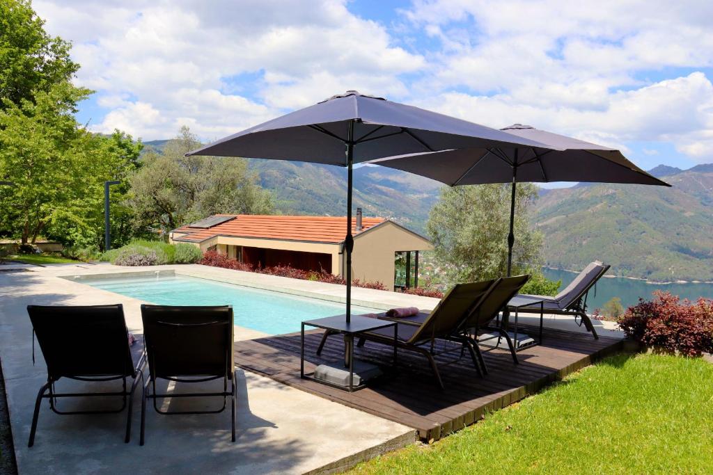 zwei Stühle und ein Tisch mit einem Sonnenschirm neben einem Pool in der Unterkunft Casa do Tempo Gerês by Gerês Casas in Vieira do Minho