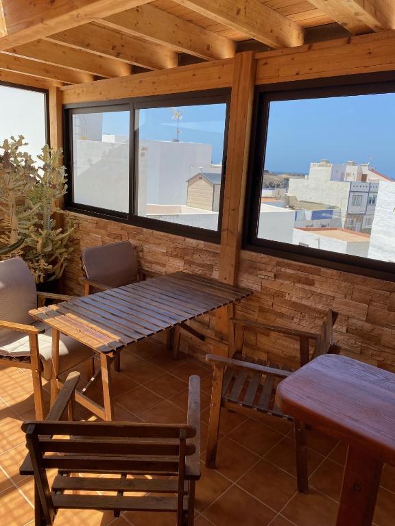a patio with a table and chairs and windows at Casa Natalie in El Cotillo