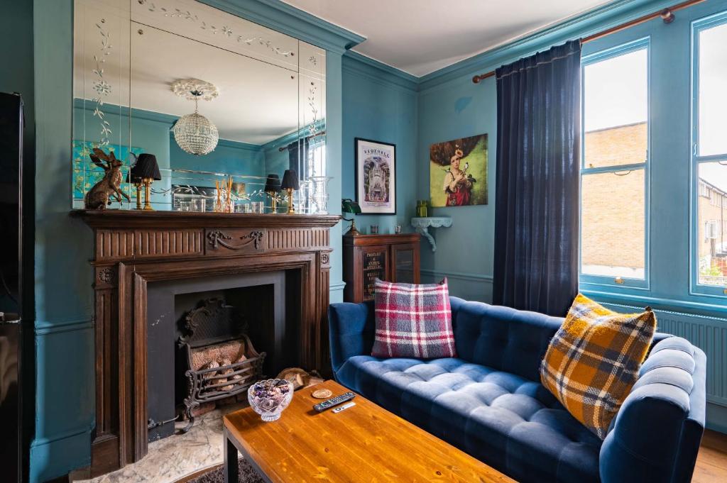 a living room with a blue couch and a fireplace at Charming home with roof terrace in East London by UnderTheDoormat in London