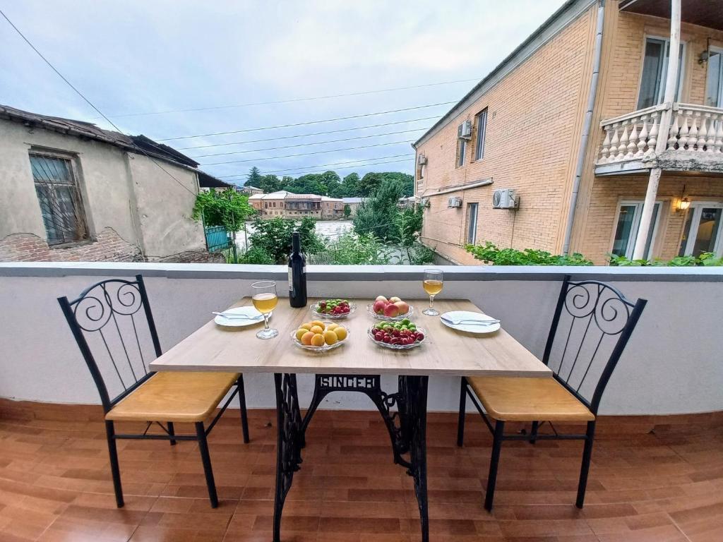 una mesa con copas de fruta y vino en el balcón en ApartHotel RioNi, en Kutaisi