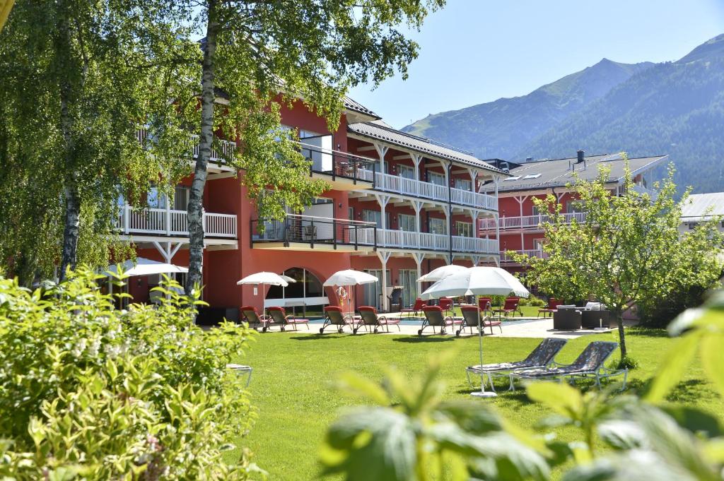 蒂羅爾州塞弗爾德的住宿－Das Hotel Eden - Das Aktiv- & Wohlfühlhotel in Tirol auf 1200m Höhe，前面设有桌子和遮阳伞的酒店