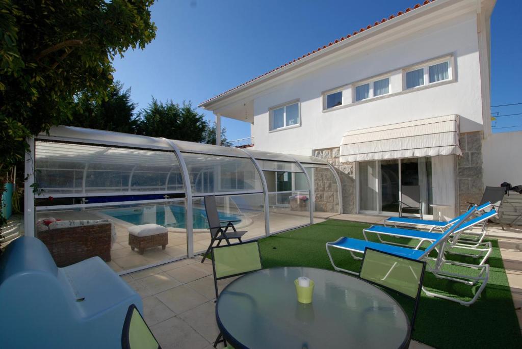 a patio with a table and chairs and a swimming pool at Seashell - House with private pool and garden in São Martinho do Porto