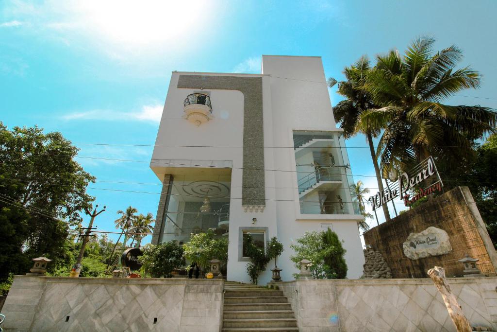 a white building with a palm tree in front of it at White Pearl Residency in Puducherry