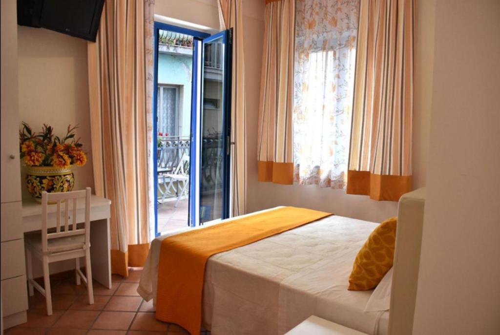 a bedroom with a bed and a table and a window at Donna Carmela - Da Rosa in Letojanni