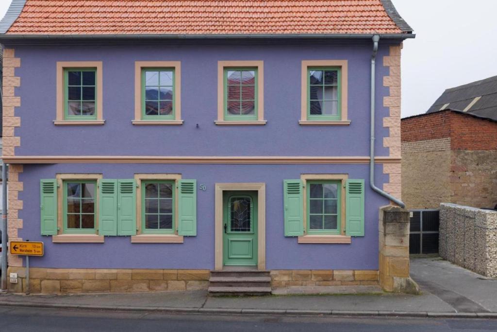 a purple house with green shutters on a street at Ferienhaus Monteverde in Meddersheim
