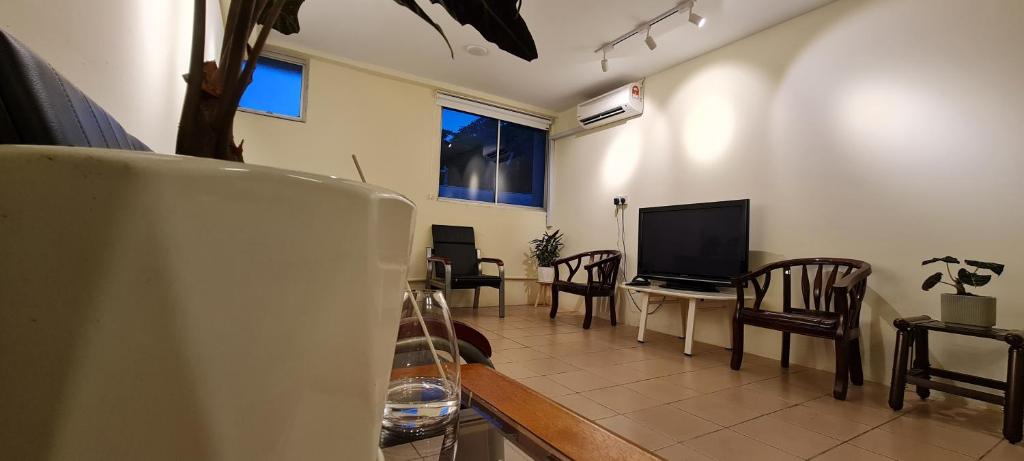 uma sala de estar com uma televisão e uma mesa e cadeiras em Misto Hotel em Kota Kinabalu