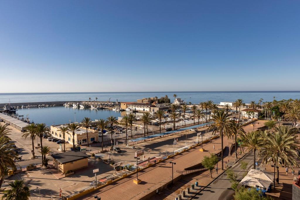 Blick auf einen Strand mit Palmen und einen Pier in der Unterkunft Las Palmeras Affiliated by FERGUS in Fuengirola