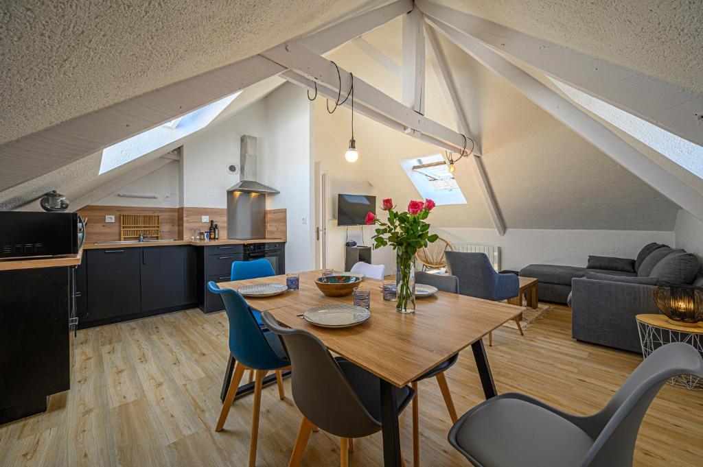 Il dispose d'une cuisine et d'un salon avec une table et des chaises en bois. dans l'établissement LE BEG ER LANN - Appartement contemporain centre ville Sarzeau, à Sarzeau