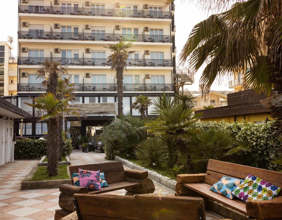 eine Hotelterrasse mit Sofas und Palmen sowie ein Gebäude in der Unterkunft Hotel Constellation in Lido di Savio