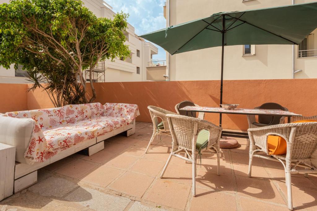 een patio met een bank en stoelen en een tafel met een parasol bij Casa Bice 2 in Golfo Aranci