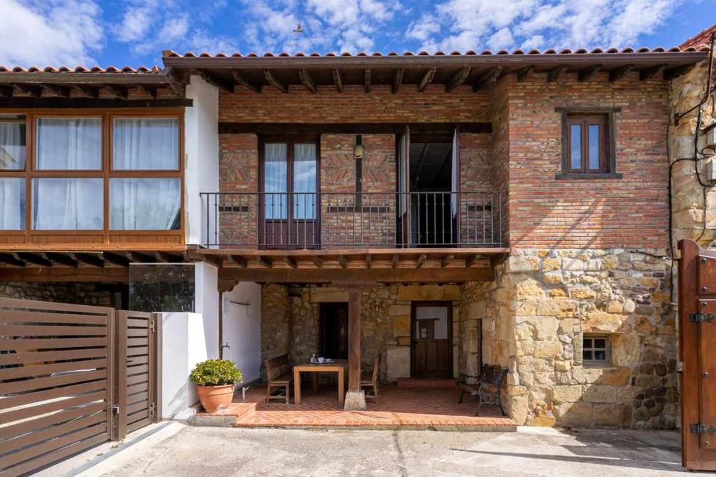 ein Backsteinhaus mit einem Balkon und einer Veranda in der Unterkunft Casa con jardín cerca de la playa El porton in Miengo
