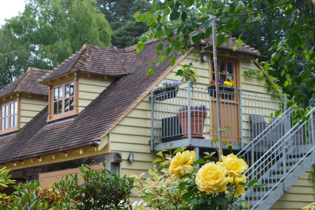 a yellow house with a balcony and yellow roses at Pinecroft Barn - Relax & Unwind! in Storrington