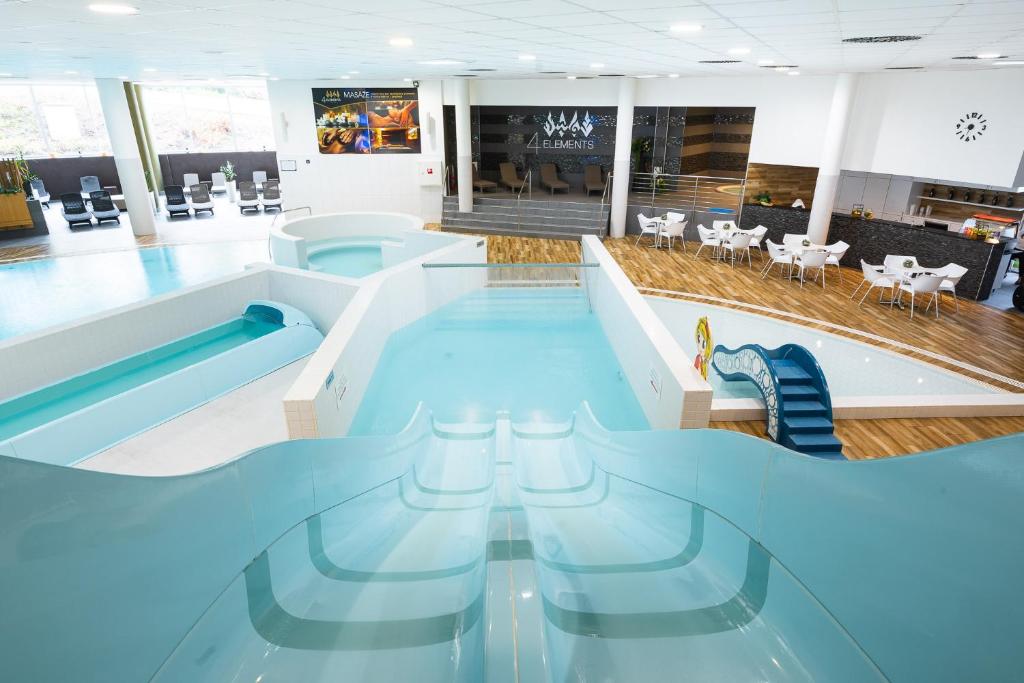 una gran piscina en una habitación con sillas y mesas en Atrium Hotel - Family friendly, en Starý Smokovec