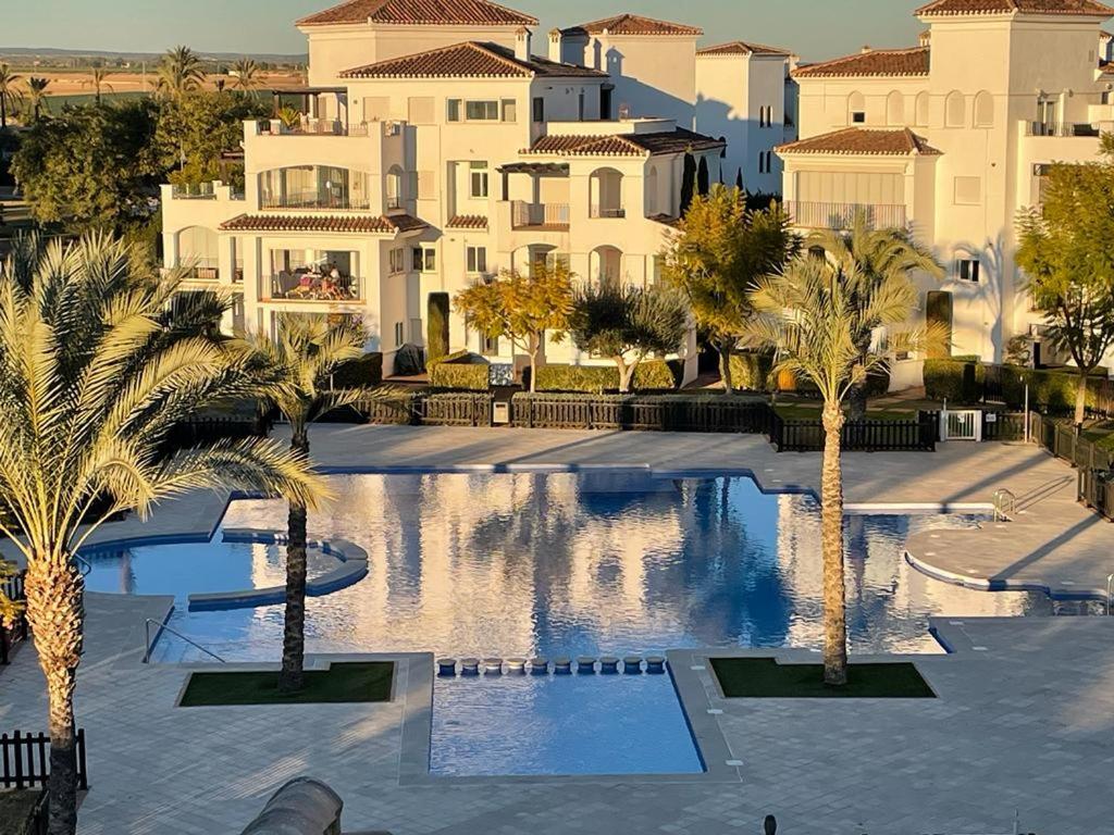 a large courtyard with palm trees and buildings at La Torre Golf Resort, Mero, Torre-Pacheco, Murcia in Murcia