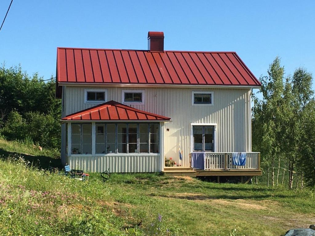 una pequeña casa blanca con techo rojo en Village Cottage In The High Coast Area 