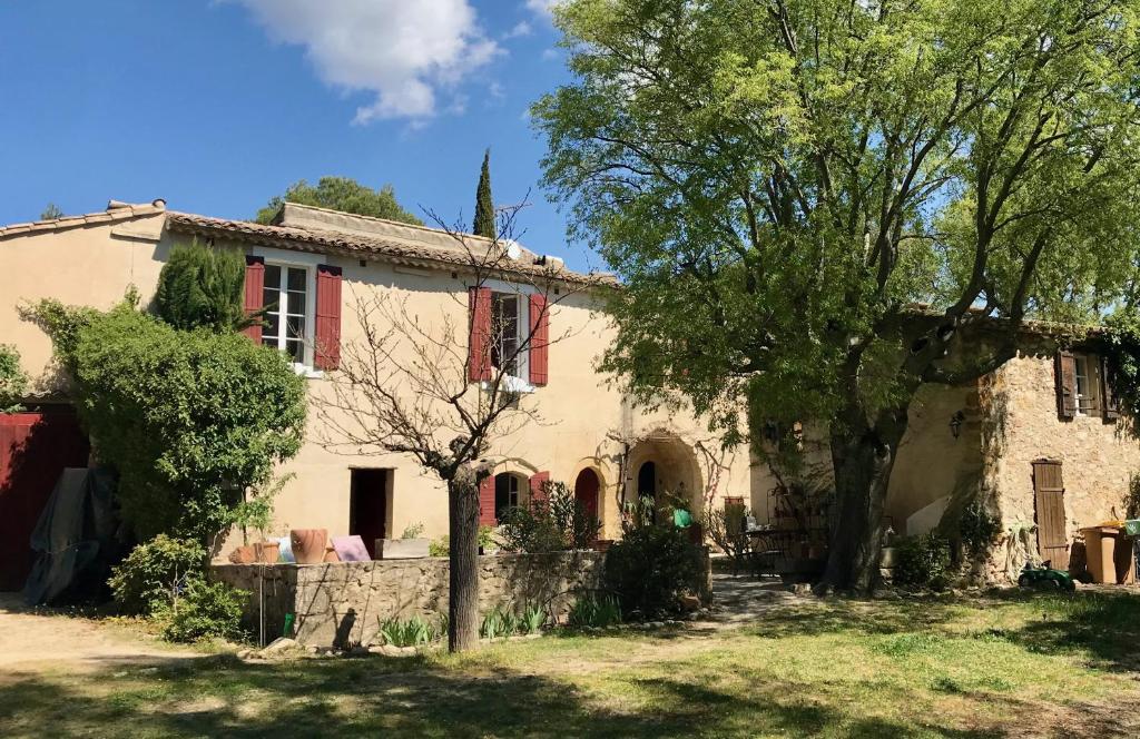 une vieille maison avec un arbre en face dans l'établissement Sous le Micocoulier, à Mérindol