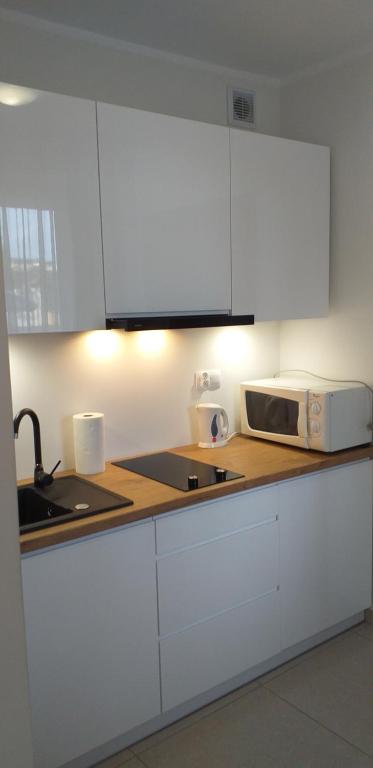 a kitchen with white cabinets and a microwave at Apartamenty Planeta 105, 108 Mielno in Mielno