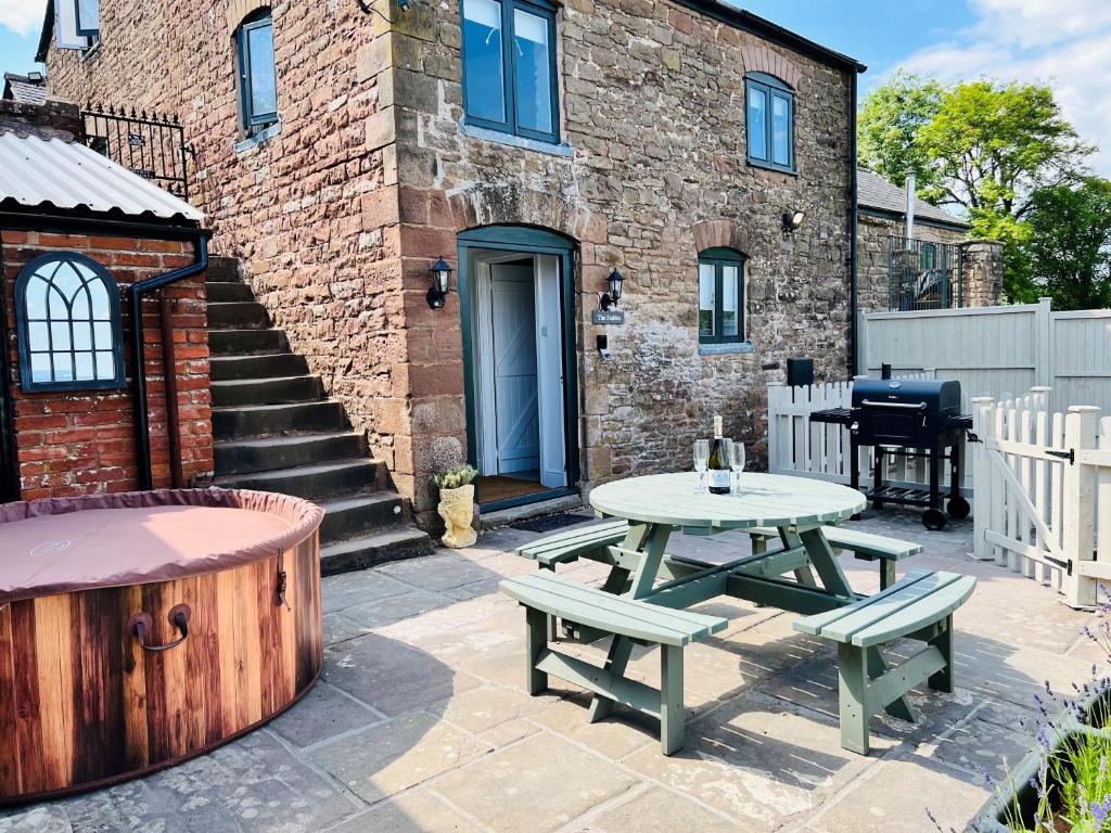 a patio with a table and benches and a grill at The Stables - Luxury Holiday Cottage in Welsh Newton Common