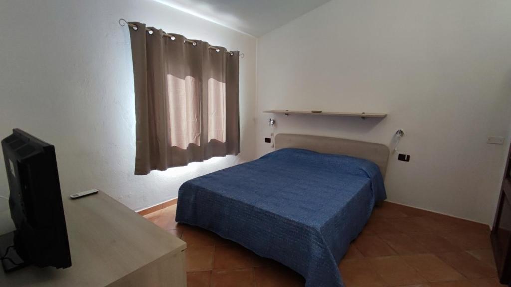 Schlafzimmer mit einem Bett und einem Flachbild-TV in der Unterkunft casa l'Ulivariu affittacamere in San Teodoro