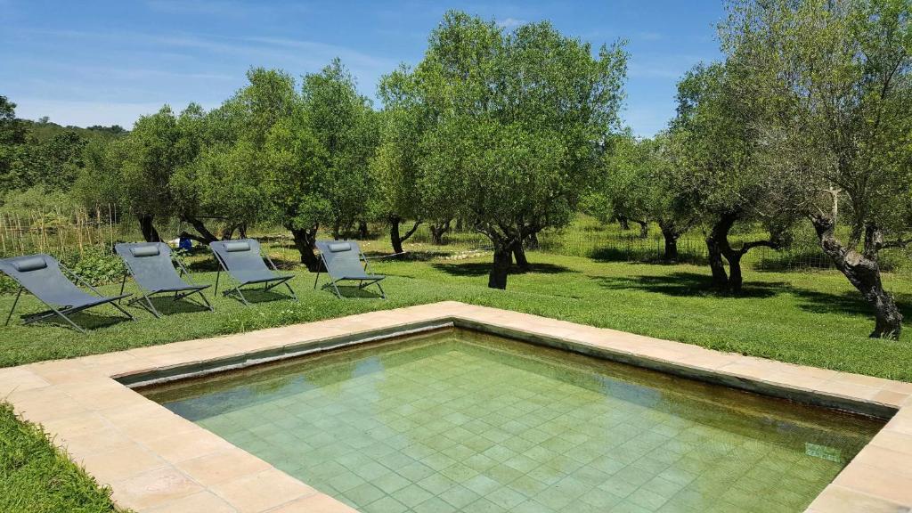 una piscina en un patio con sillas y árboles en Casa rural con jardín privado, en Navata