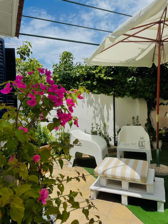 a patio with two white chairs and pink flowers at Alemar Bed & Breakfast in Mondello
