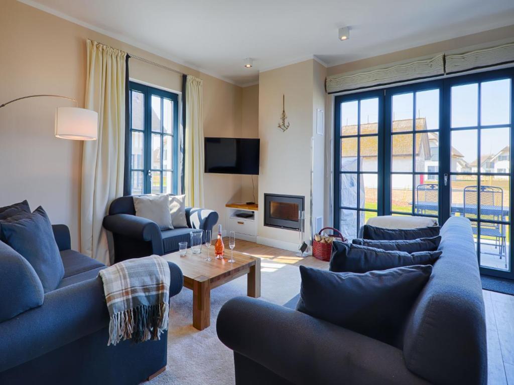 a living room with blue couches and a table at Reetland am Meer - Luxus Reetdachvilla mit 3 Schlafzimmern, Sauna und Kamin F18 in Dranske