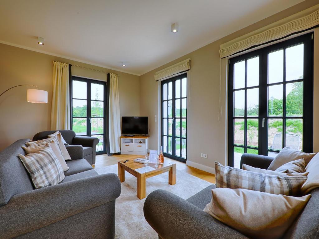 a living room with two couches and a tv at Reetland am Meer - Superior Reetdachvilla mit 2 Schlafzimmern F25 in Dranske