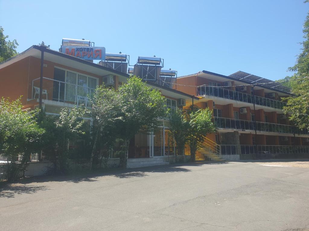 a large red building with trees in front of it at Hotel Maria in Kiten