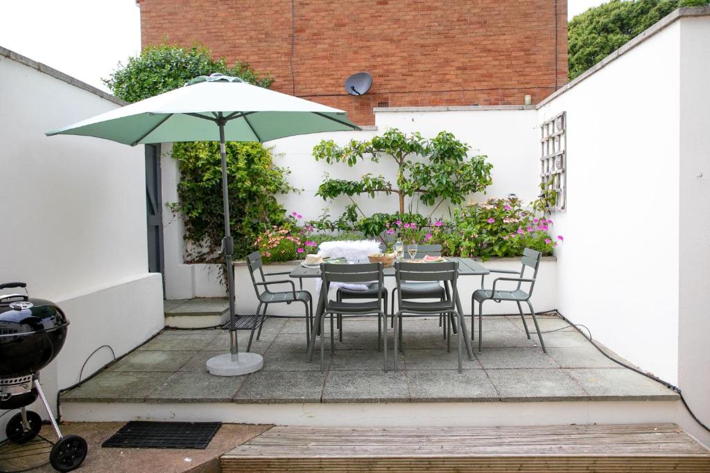 a patio with a table and chairs and an umbrella at Poplar Cottage, Budleigh Salterton in Budleigh Salterton