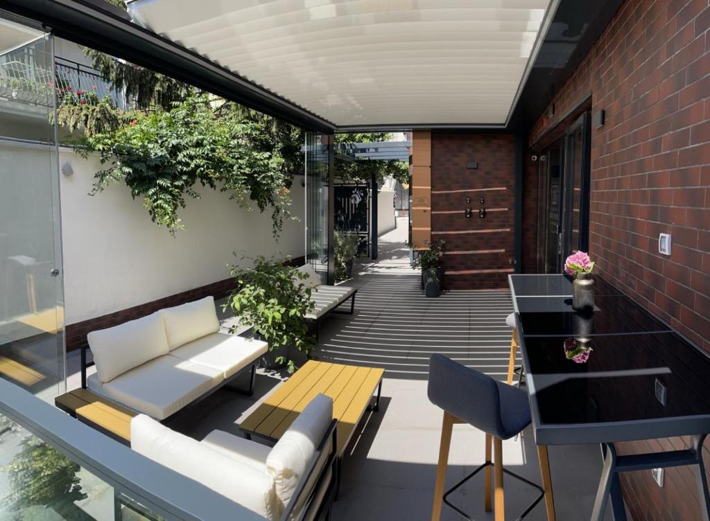 un patio al aire libre con muebles blancos y plantas en Caro Apartments & Rooms en Varna