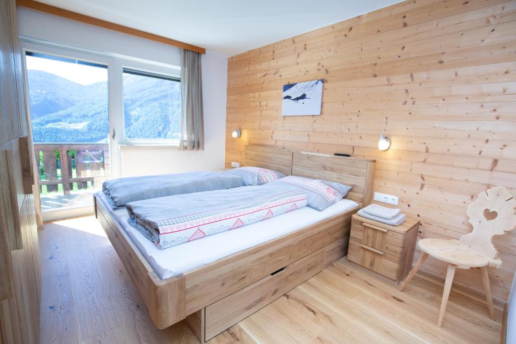 a bedroom with a bed and a wooden wall at Ferienwohnung Jörgenhof in Telfes im Stubai
