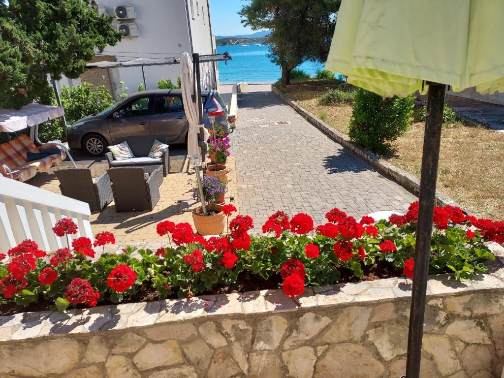 a garden with red flowers in a stone wall at Beach House in Betina