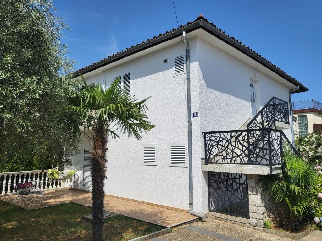 een wit huis met een palmboom ervoor bij Modern Apartment Tara with Parking in Malinska