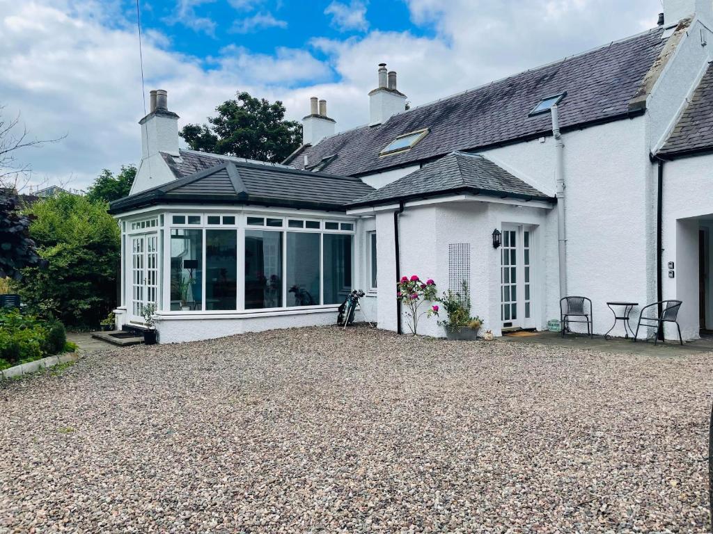 a white house with a conservatory and a gravel driveway at Lovely 5-Bed House in Lundin Links coastal village in Lundin Links
