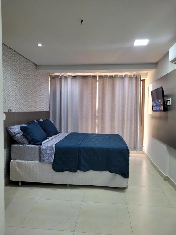 a bedroom with a bed with blue sheets and a window at Espetacular Apart hotel Manaira in João Pessoa