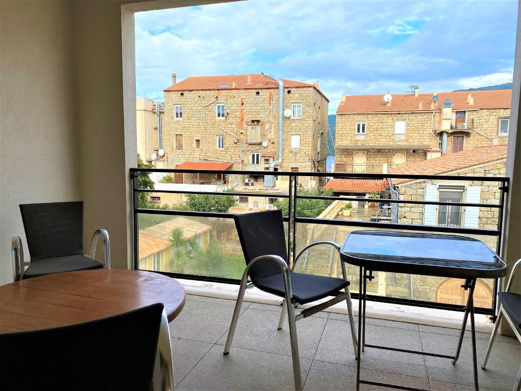 d'un balcon avec une table, des chaises et une grande fenêtre. dans l'établissement PORTO PIANO 2 pièces en centre-ville, à Propriano