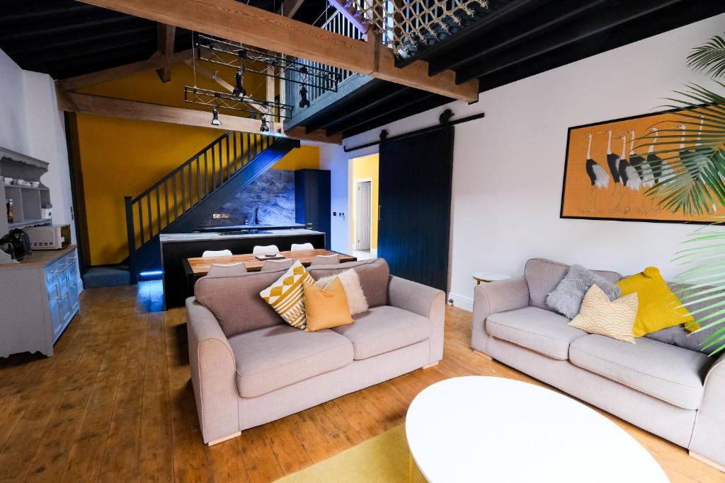 a living room with two couches and a table at The Eden Warehouse - Gold Apartment, sleeps 5 in Southport
