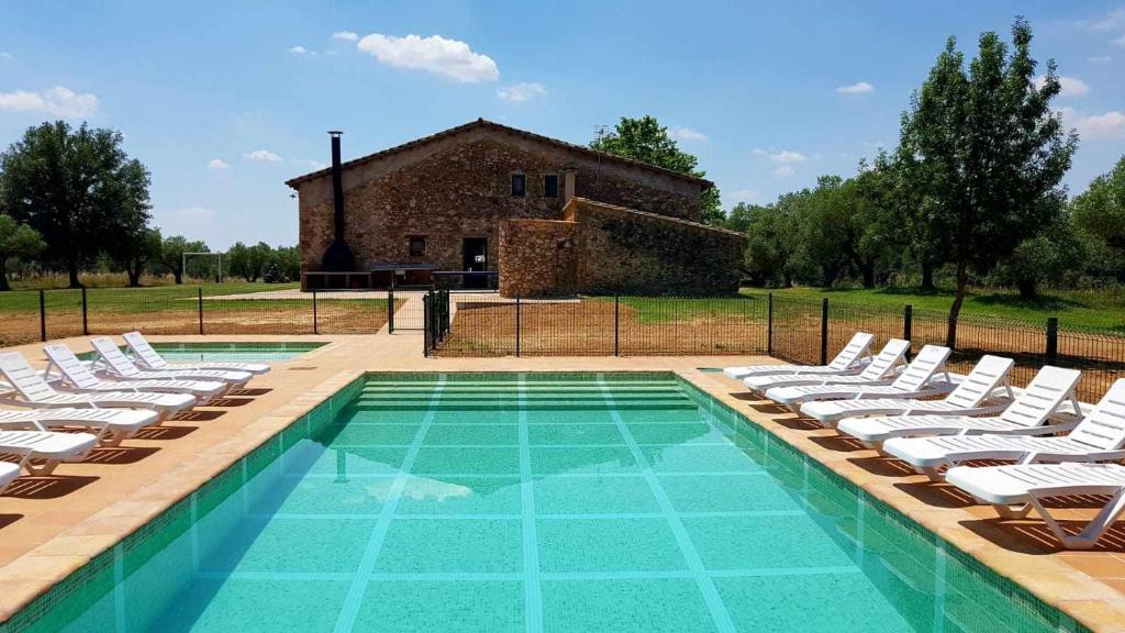 a swimming pool with lounge chairs and a building at Masía para grupos con piscina privada-28 pax in Girona