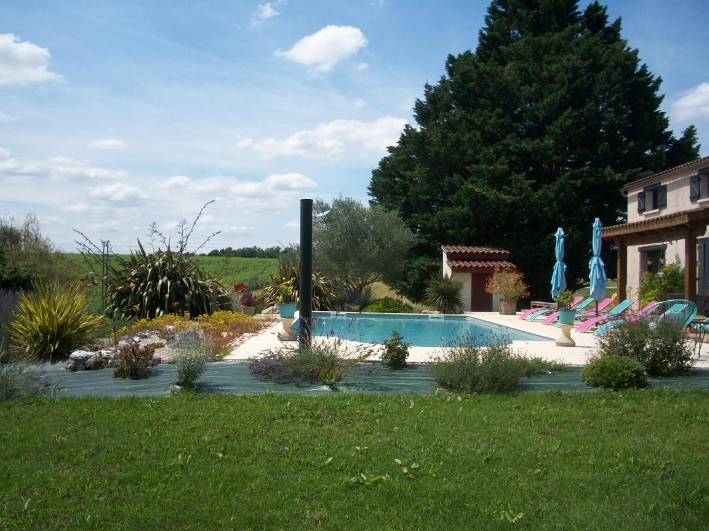 a swimming pool in a yard next to a house at Le Pré Joli in Beaugas