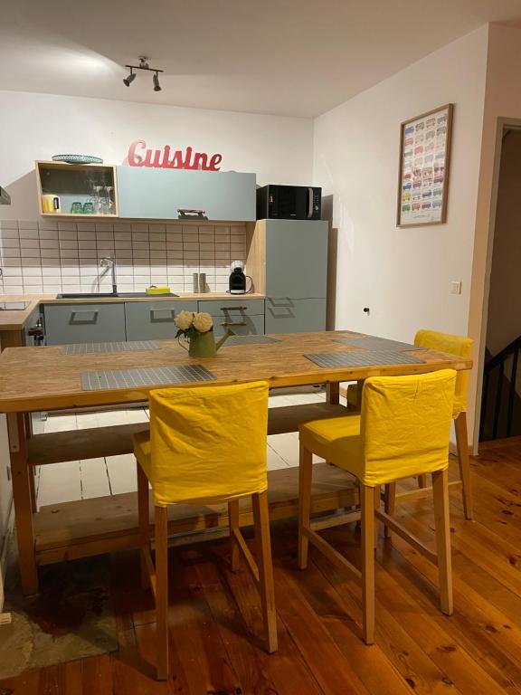 a kitchen with a wooden table and two yellow chairs at Maison de ville dans le centre historique de Cahors - Cosy townhouse in the historical center of Cahors in Cahors