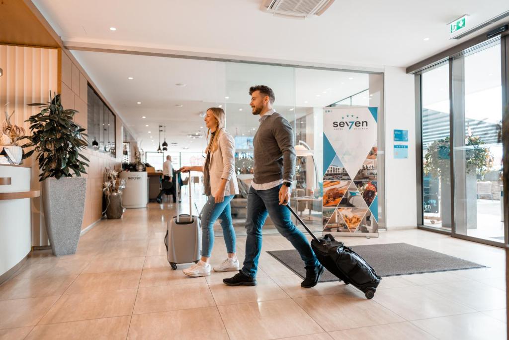 un hombre y una mujer caminando por un centro comercial con equipaje en Hotel Seven, en Villach